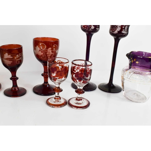 134 - A group of coloured bohemian glassware, to include pair of green and gilded bud vases, red painted g... 