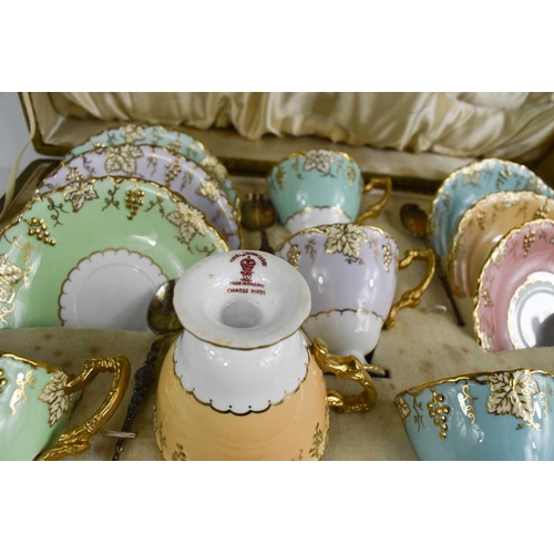 143 - A cased set of Royal Crown Derby tea cups and saucers, in a variety of colours, shaped with vine pat... 