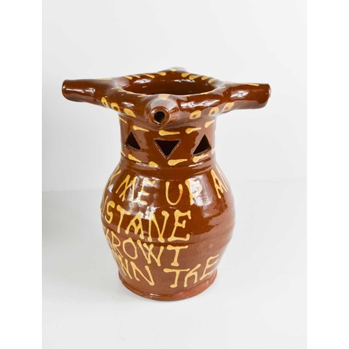 172 - A terracotta slipware glazed puzzle jug, with three spouts, and bearing the inscription 'Drink me up... 