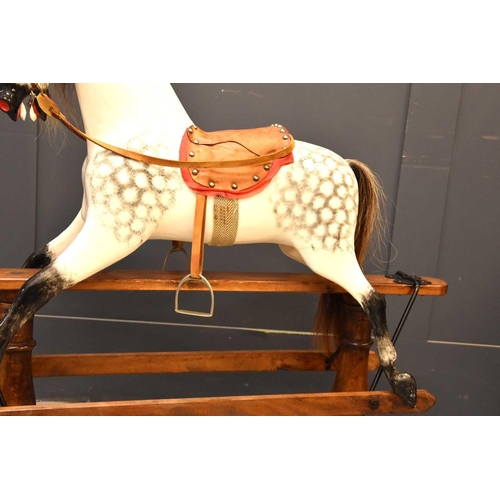 285 - A vintage rocking horse on a pine stained base. the dapple grey hand painted horse with leather sadd... 