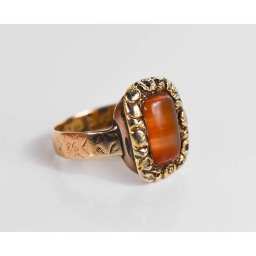 41 - A 12ct gold Georgian ring, set with an agate cabochon bordered by floral worked setting, on an engra... 