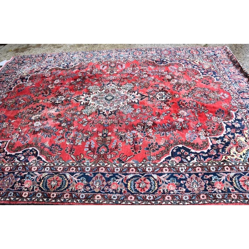 539 - A large wool rug of Persian design, the red ground with central lozenge and foliate and arabesque bo... 