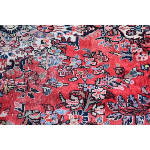 539 - A large wool rug of Persian design, the red ground with central lozenge and foliate and arabesque bo... 