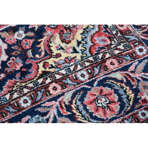 539 - A large wool rug of Persian design, the red ground with central lozenge and foliate and arabesque bo... 