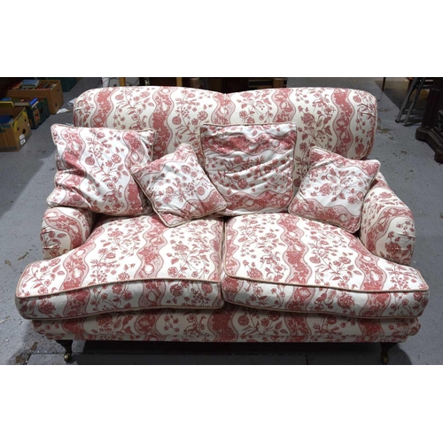 585 - A two seater sofa in the style of Howard and Sons, upholstered in cream and red fabric decorated wit... 