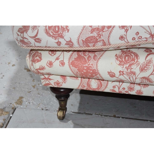 585 - A two seater sofa in the style of Howard and Sons, upholstered in cream and red fabric decorated wit... 