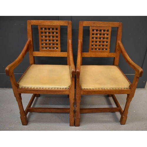 587 - A pair of Rabbit Man adzed oak carver chairs, with lattice backs, with downswept arms and leather pa... 