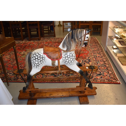 285 - A vintage rocking horse on a pine stained base. the dapple grey hand painted horse with leather sadd... 