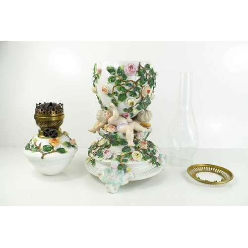 223 - A German porcelain oil lamp, the body modelled with cherubs and flowers.