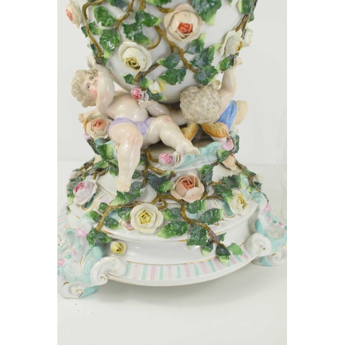 223 - A German porcelain oil lamp, the body modelled with cherubs and flowers.