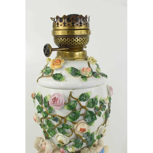 223 - A German porcelain oil lamp, the body modelled with cherubs and flowers.