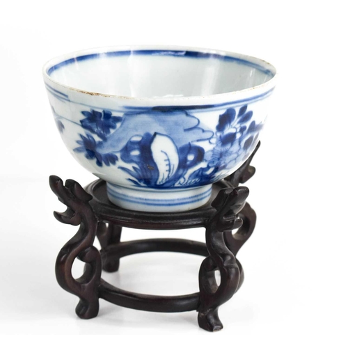 241 - A 19th century Chinese blue and white bowl decorated with flowers, and raised on a wooden carved sta... 