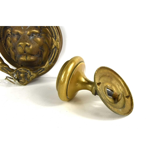 329 - An antique brass lions head door knocker together with a brass door handle.