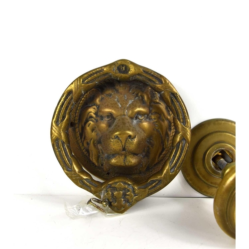 329 - An antique brass lions head door knocker together with a brass door handle.