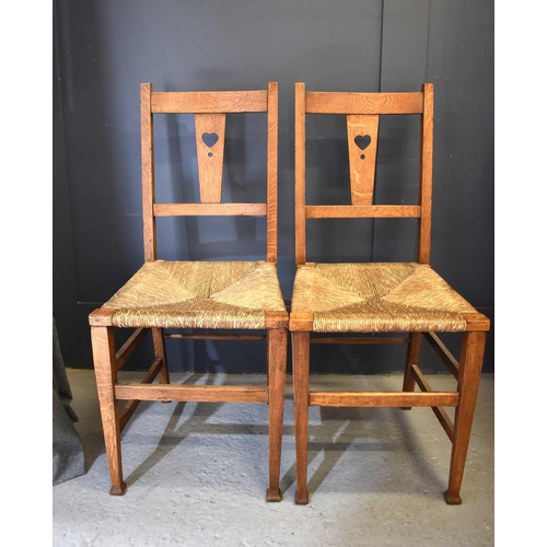 495 - A pair of Shaker style oak chairs, circa 1920, the splats with pierced heart motifs and raised on sq... 