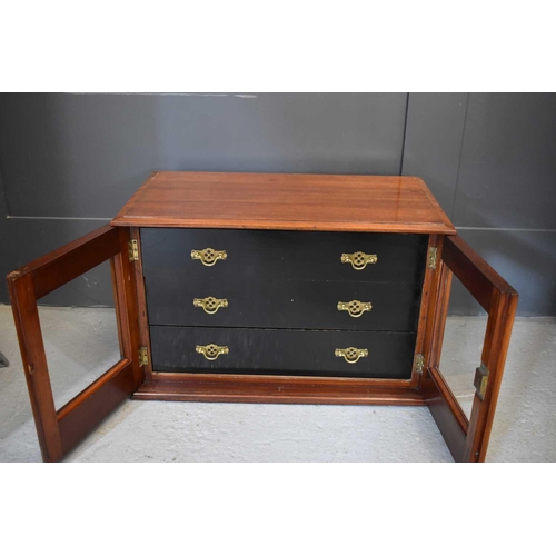 499 - An Edwardian mahogany collectors cabinet with ebonised interior drawers enclosed by glass doors.