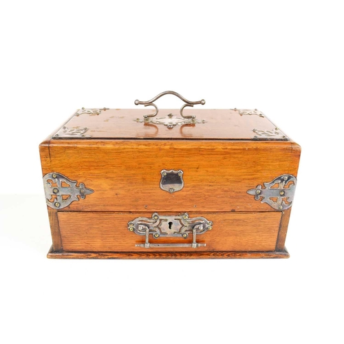 23 - An Edwardian oak smokers compendium, with sliding top and drawer, with compartments throughout, and ... 