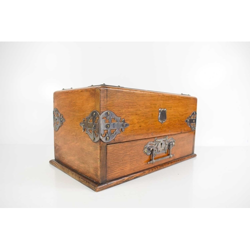 23 - An Edwardian oak smokers compendium, with sliding top and drawer, with compartments throughout, and ... 