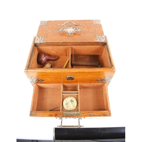 23 - An Edwardian oak smokers compendium, with sliding top and drawer, with compartments throughout, and ... 