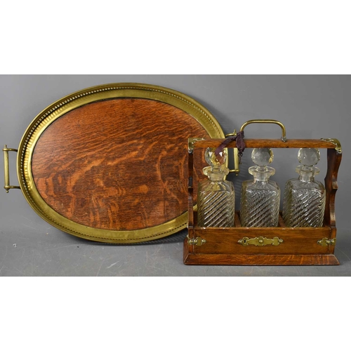 250 - A Victorian oak cased tantalus, with three cut glass decanters, the case clad with brass and having ... 