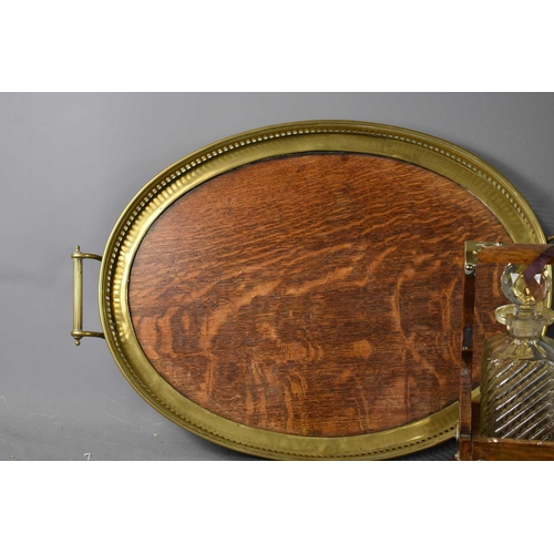 250 - A Victorian oak cased tantalus, with three cut glass decanters, the case clad with brass and having ... 