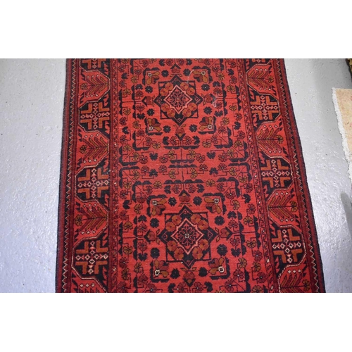 255 - A very long wool runner, the red ground with geometric stylised motifs 81 by 500cm.