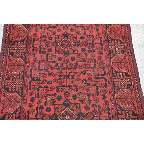 255 - A very long wool runner, the red ground with geometric stylised motifs 81 by 500cm.