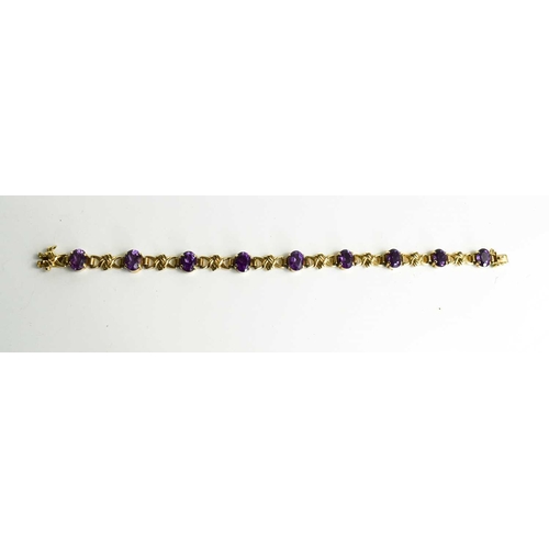 143 - A 9ct gold and amethyst bracelet with nine oval cut amethysts, 21cm long.