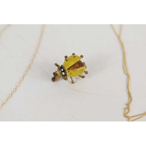 184 - Two 9ct gold necklaces together with a gilt metal and amber lady bug brooch and a yellow metal penda... 