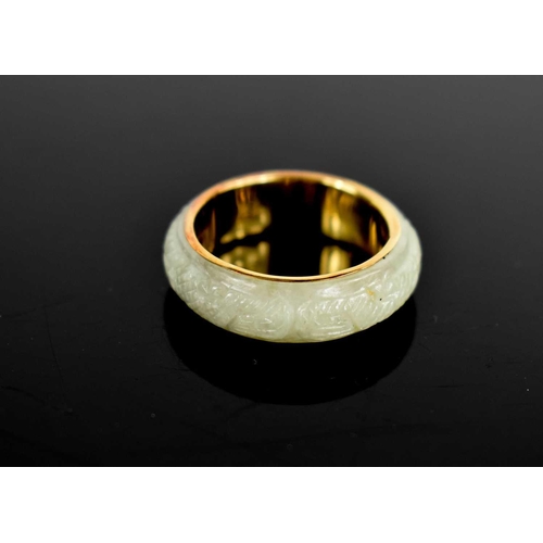 21 - A 14ct gold and jade Chinese ring, with pierced symbols to the inside of the band, and carving to th... 