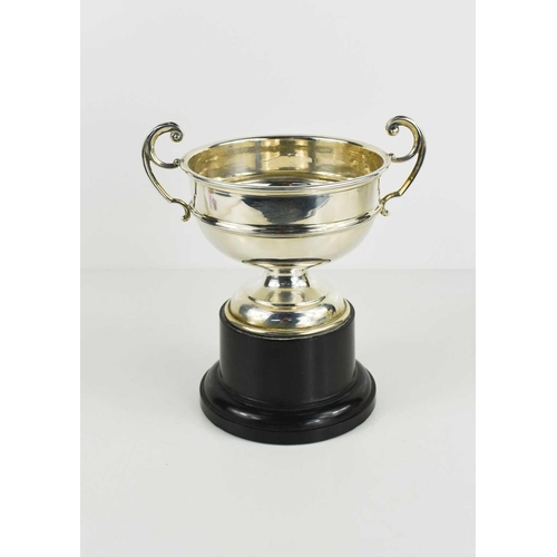 454 - A silver twin handled trophy raised on an ebonised plinth, Birmingham 1937, 16cm high.