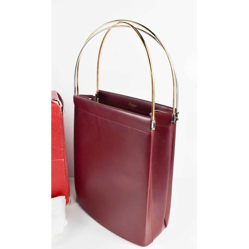 479 - A Cartier Handbag of concertina form in burgundy leather with three arched tri-gold coloured metal h... 