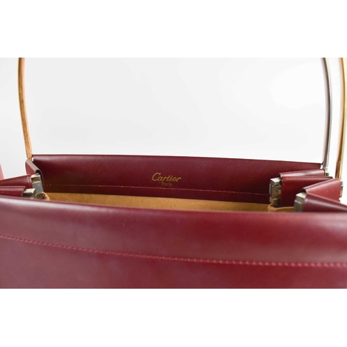 479 - A Cartier Handbag of concertina form in burgundy leather with three arched tri-gold coloured metal h... 