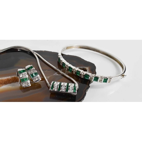 6 - A 14ct white gold, diamond and emerald demi parure, consisting a bangle set with seven baguette cut ... 