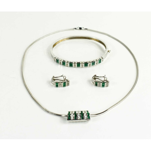 6 - A 14ct white gold, diamond and emerald demi parure, consisting a bangle set with seven baguette cut ... 