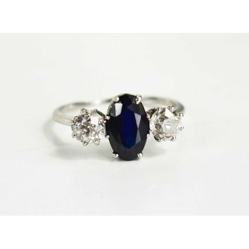 9 - A diamond and sapphire three stone ring, with central oval cut dark sapphire of approximately 9.4 by... 