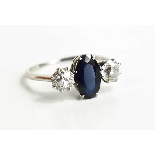 9 - A diamond and sapphire three stone ring, with central oval cut dark sapphire of approximately 9.4 by... 