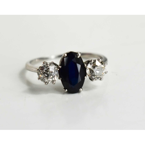 9 - A diamond and sapphire three stone ring, with central oval cut dark sapphire of approximately 9.4 by... 