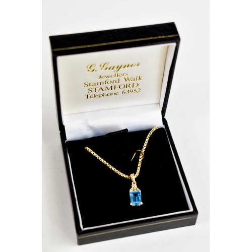 94 - A 14ct gold and blue topaz pendant, the emerald cut stone of approximately 8.1 by 6.0mm, with 14ct g... 