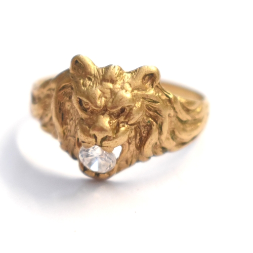 84a - A 9ct gold ring modelled as a lions head, its open mouth holding a Cubic Zirconia, 3.21g.