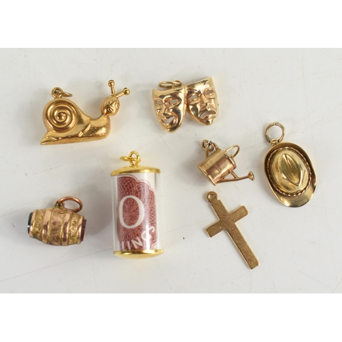 42a - A group of six 9ct gold charms, comprising a snail, watering can, theatrical masks, a stetson and a ... 