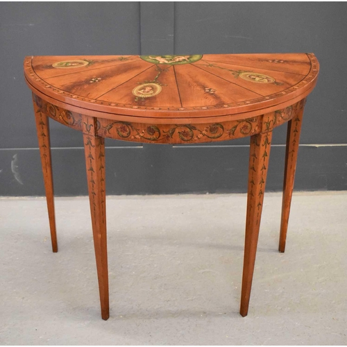 516 - A 19th century satinwood painted demi-lune card table, the top decorated with painted putti, ribbon ... 