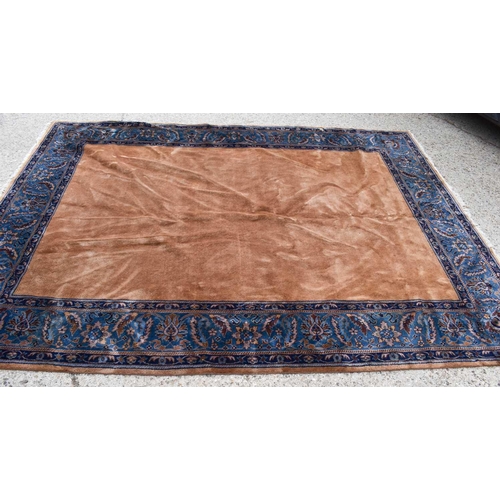 519 - An Indian wool carpet, in mustard brown with blue border, 276 by 363cm.