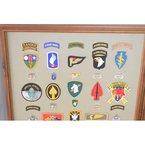 56 - Two framed panels of military cloth patches and metal badges to include US special forces and airbor... 