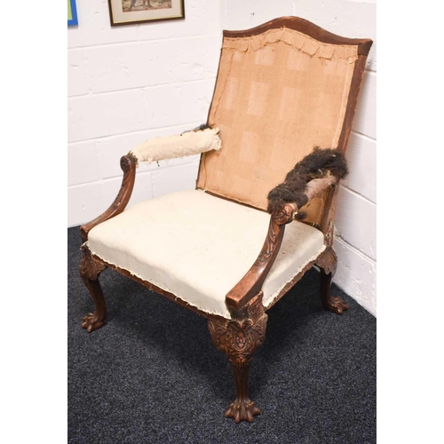 568 - An 18th century and later walnut framed armchair, lacking upholstery, the wide carved arms adjoining... 