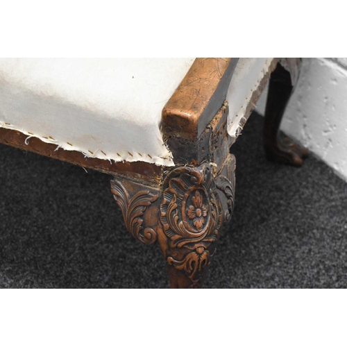 568 - An 18th century and later walnut framed armchair, lacking upholstery, the wide carved arms adjoining... 