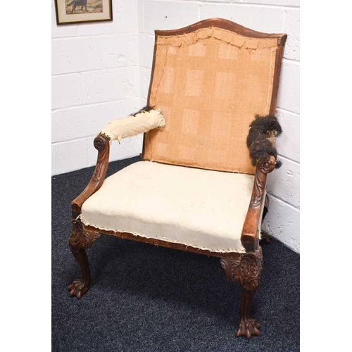 568 - An 18th century and later walnut framed armchair, lacking upholstery, the wide carved arms adjoining... 