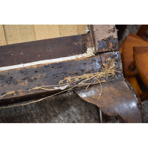 568 - An 18th century and later walnut framed armchair, lacking upholstery, the wide carved arms adjoining... 