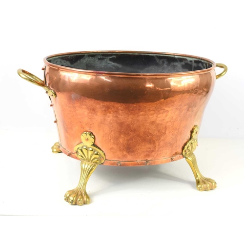 116 - A large copper and brass coal bucket, twin handles and raised on four lion paw feet, 29cm high by 42... 