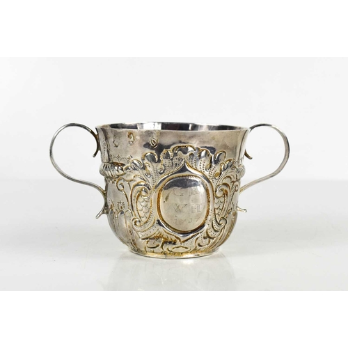 134 - A Queen Anne period twin handled silver cup, bearing the initials GR, WH and dated 1717, embossed wi... 